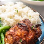 Pinterest graphic for Air Fryer Chicken Thighs recipe. Text says, "Air Fryer Chicken Thighs simplejooy.com." Image shows Air Fryer Chicken Thigh served on a plate with rice and green beans.