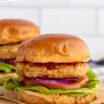 Pinterest graphic for Air Fryer Turkey Burgers recipe. Text says, "Air Fryer Turkey Burgers simplejoy.com." Image shows side view of Air Fryer Turkey Burgers served on buns with lettuce, tomato, onion, and ketchup.