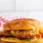 Pinterest graphic for Chicken Sandwich recipe. Text says, "the best Chicken Sandwich simplejoy.com." Image shows side view of Chicken Sandwich served on a bun with chick fil a sauce and pickles.