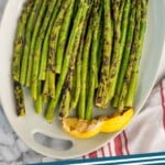 Pinterest graphic for Grilled Asparagus recipe. Image shows overhead view of a platter of Grilled Asparagus garnished with lemon wedges. Text says, "Grilled Asparagus simplejoy.com"