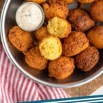Pinterest graphic for Hush Puppies recipe. Image is overhead view of a bowl of Hush Puppies with dipping sauce. Text says, "Hush Puppies simplejoy.com."