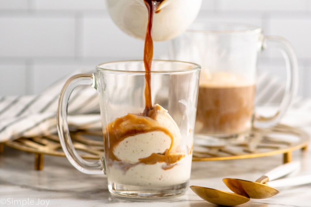 Side view of coffee being poured into a mug of ingredients for Affogato recipe. Spoons beside.