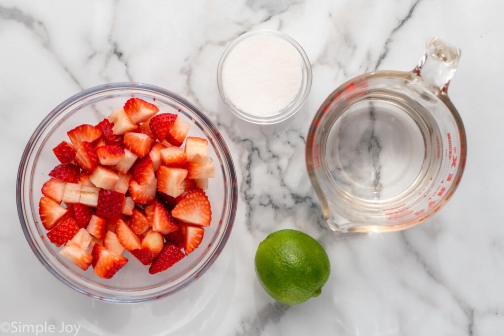 Overhead view of ingredients on countertop for strawberry Agua Fresca recipe.