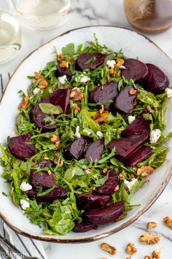 Platter with Beet Salad garnished with goat cheese crumbles and walnuts. Dressing beside.
