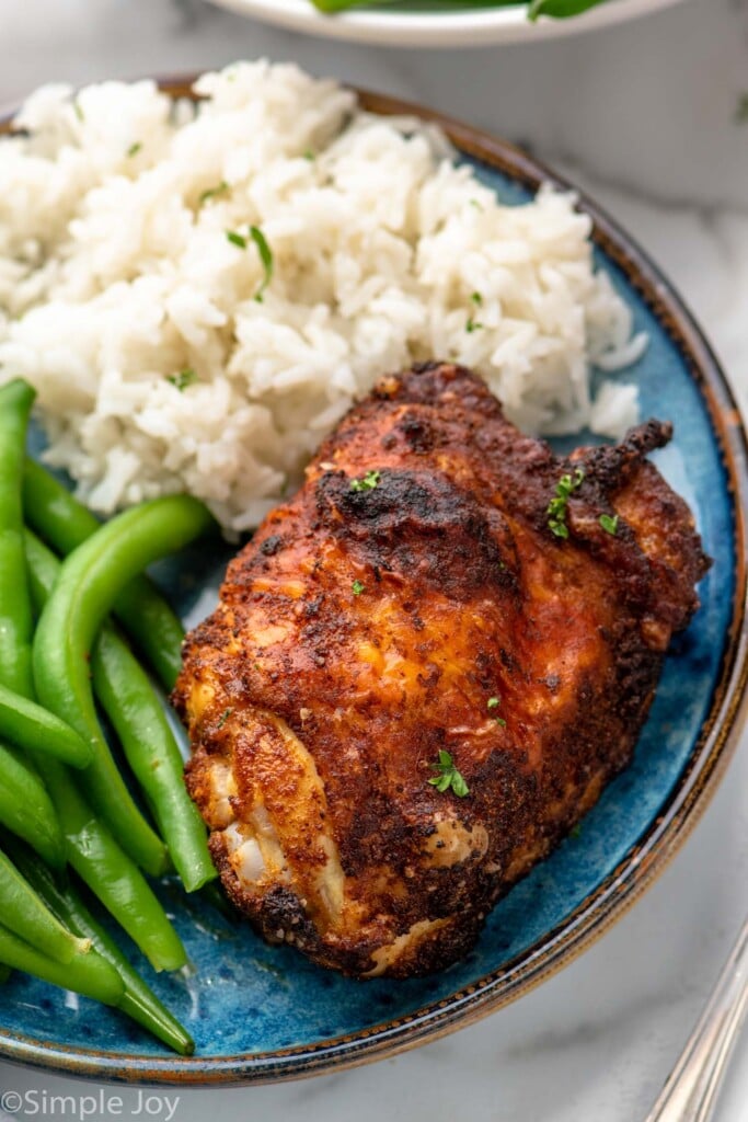 Air Fryer Chicken Thigh served on a plate with rice and green beans.