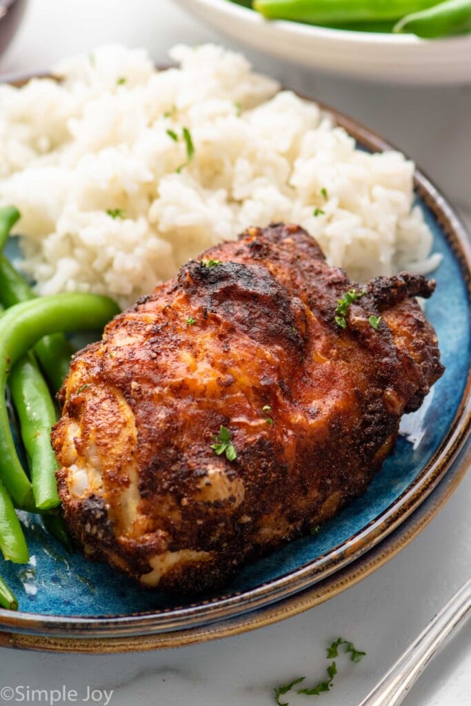 Air Fryer Chicken Thigh served on a plate with rice and green beans.