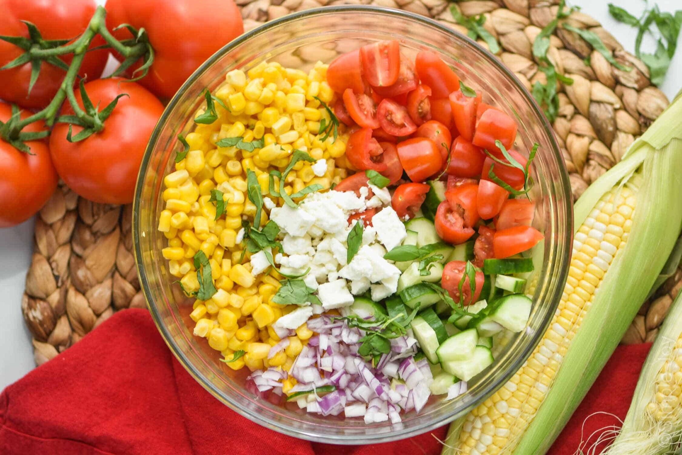 overhead view of a glass bowl full of the ingredients for corn salad recipe divided up