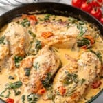 Skillet of Tuscan Chicken with cherry tomatoes beside.