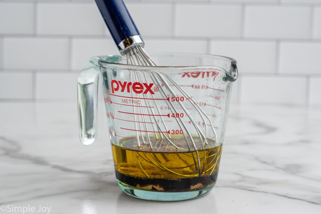 Measuring cup of dressing for Beet Salad recipe with whisk to mix.
