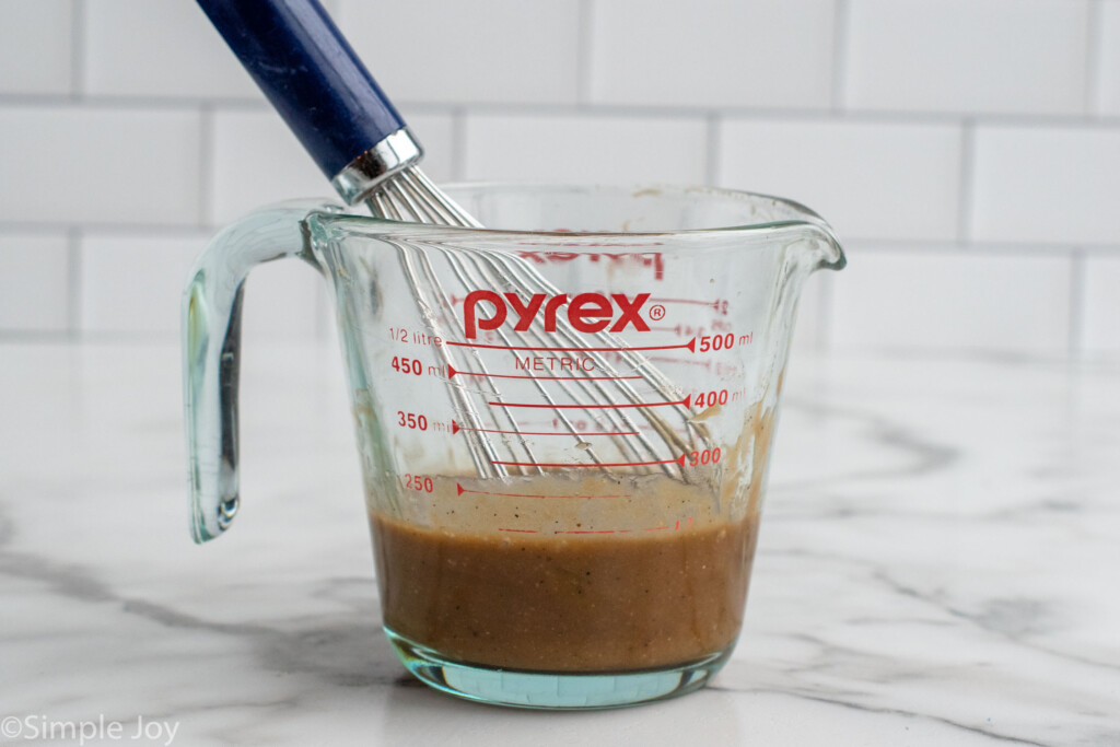 Measuring cup of dressing for Beet Salad with whisk after mixing.