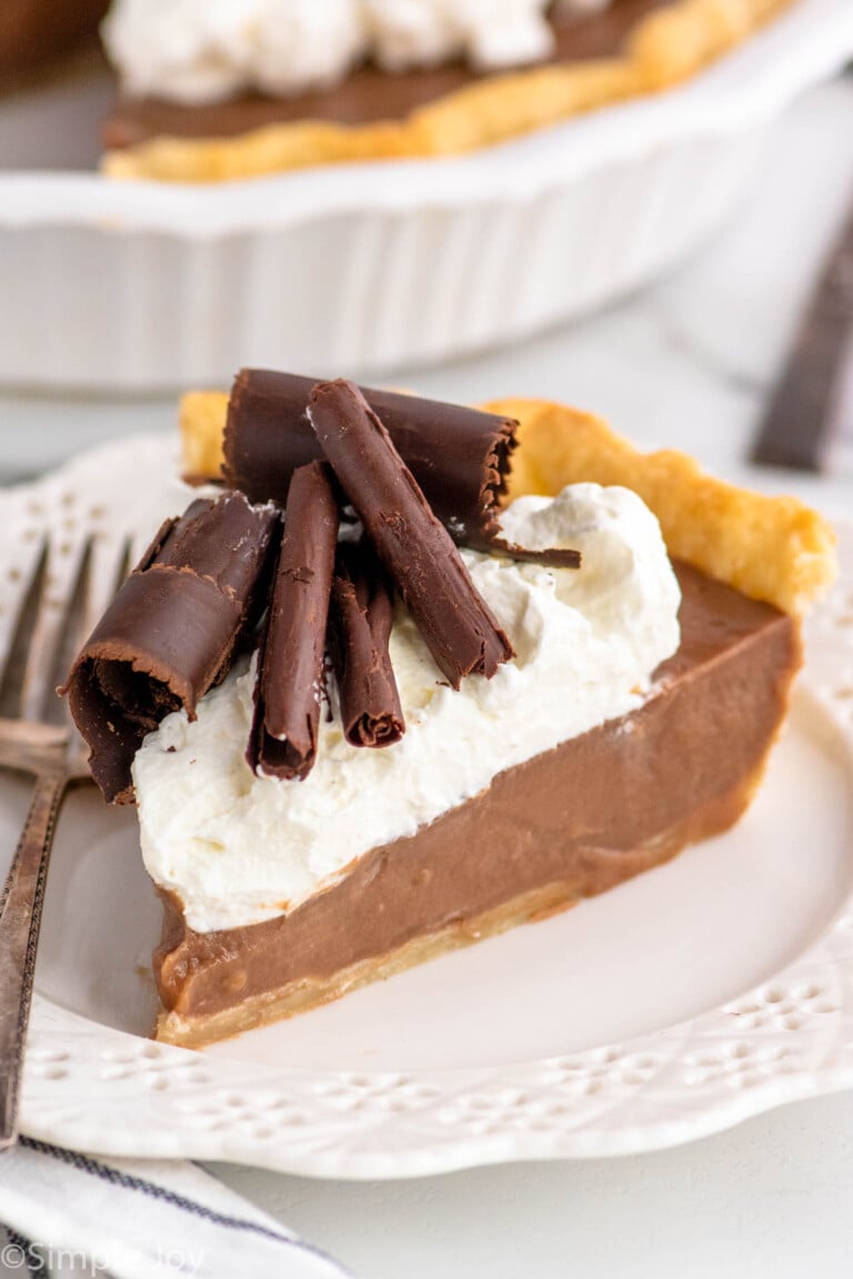 Slice of Chocolate Cream Pie garnished with whipped cream and chocolate shavings served on a plate with a fork.