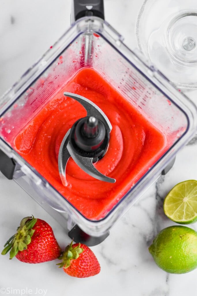 Overhead view of blender with Strawberry Margarita recipe, strawberries and limes beside. - 5