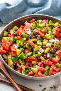 Bowl of Greek Salad with dressing, feta cheese, and seasonings.