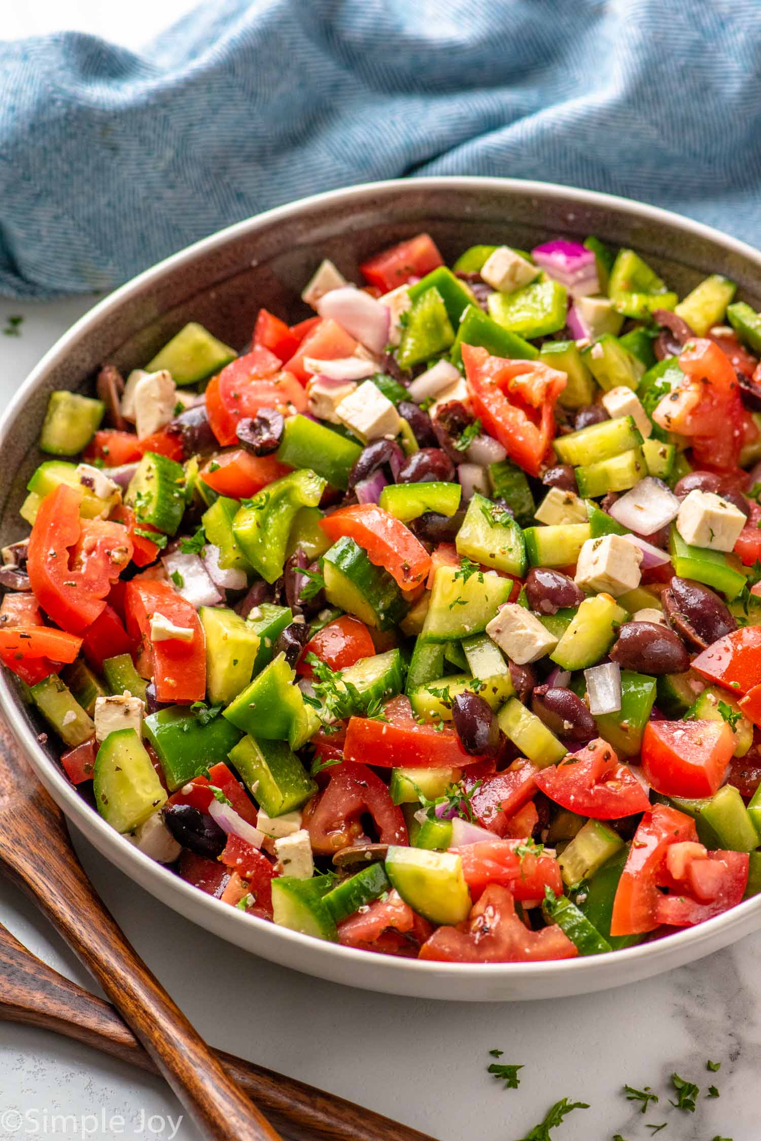 Bowl of Greek Salad with dressing, feta cheese, and seasonings.