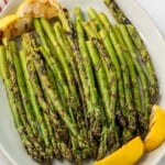 Platter of Grilled Asparagus garnished with lemon wedges.