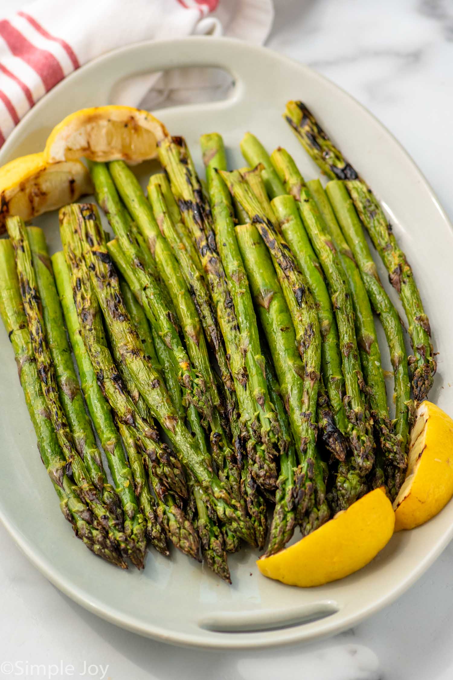 Platter of Grilled Asparagus garnished with lemon wedges.