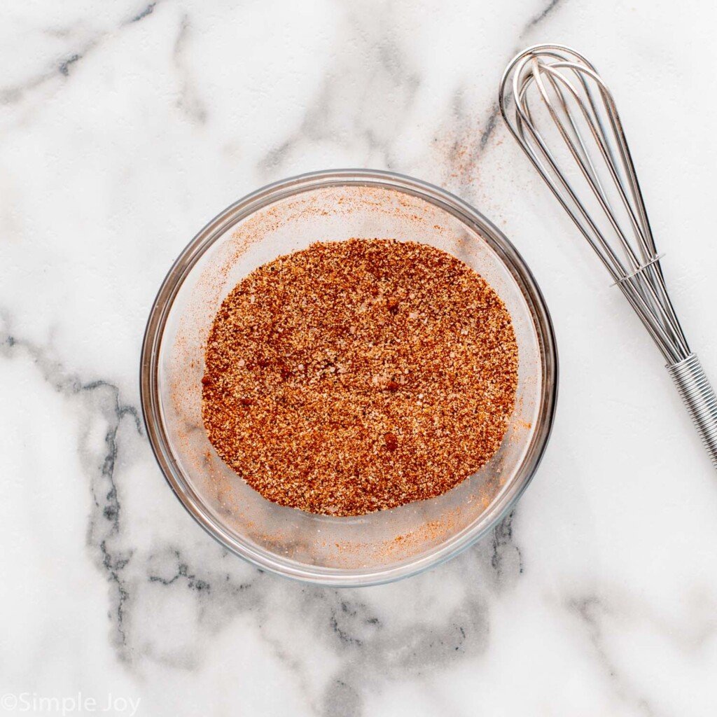 Overhead view of a bowl of seasoning with whisk beside for Air Fryer Chicken Thighs recipe.