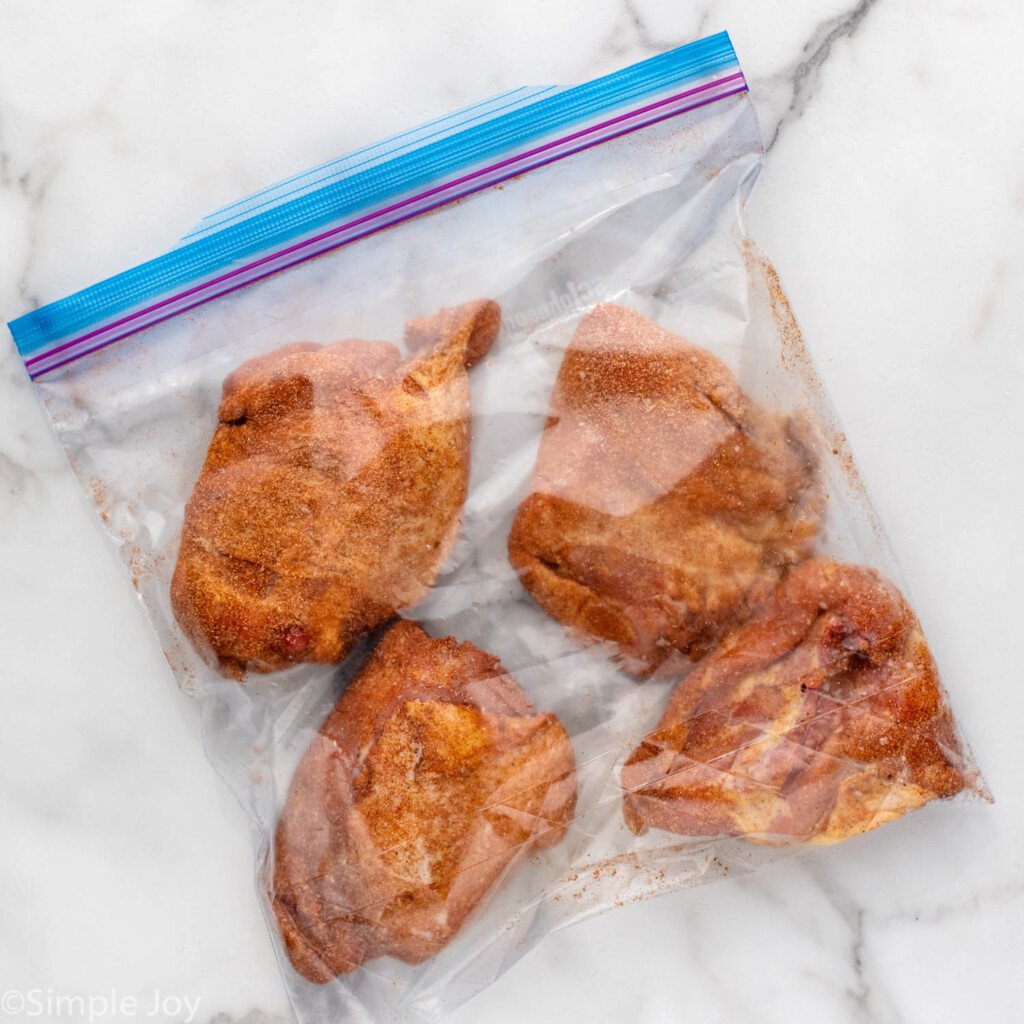 Overhead view of seasoned chicken thighs in plastic bag for Air Fryer Chicken Thighs recipe.
