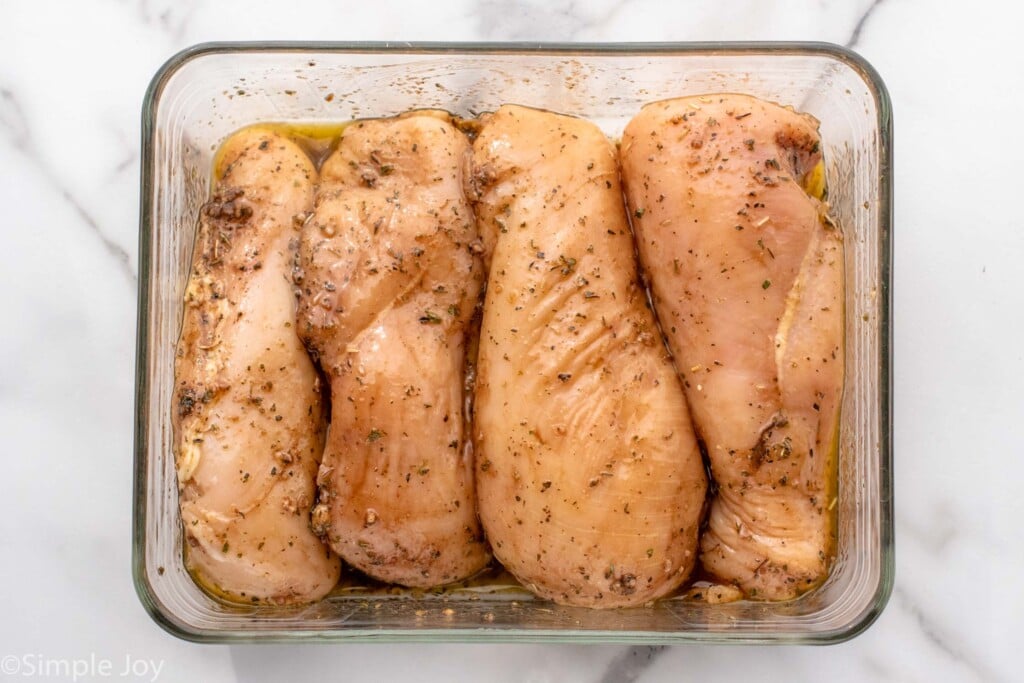 Overhead view of raw chicken breasts in marinade for Bruschetta Chicken recipe.
