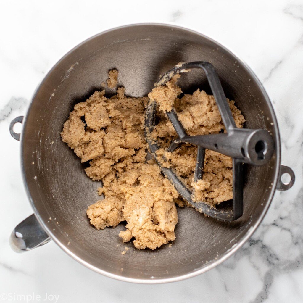 overhead of mixing bowl of Chocolate Chip Cookie Bars ingredients with mixer attachment