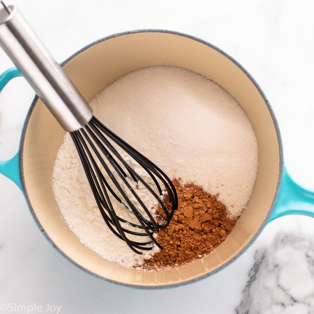 Overhead view of ingredients with a whisk in a saucepan for Chocolate Cream Pie recipe