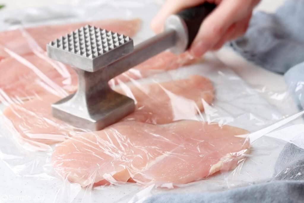 a meat mallet pounding chicken cutlets thin