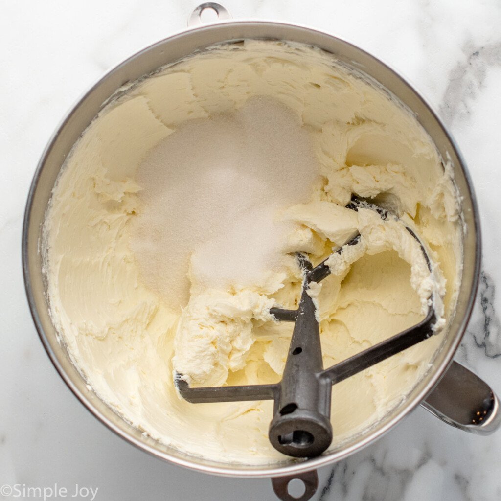 Overhead view of mixing bowl and beaters with cream cheese mixture for Strawberry Cheesecake recipe.
