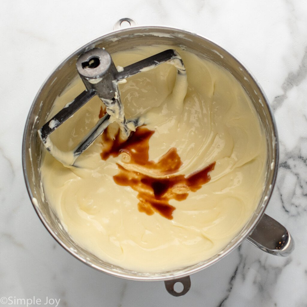 Overhead view of mixing bowl and beaters with cream cheese mixture for Strawberry Cheesecake recipe.