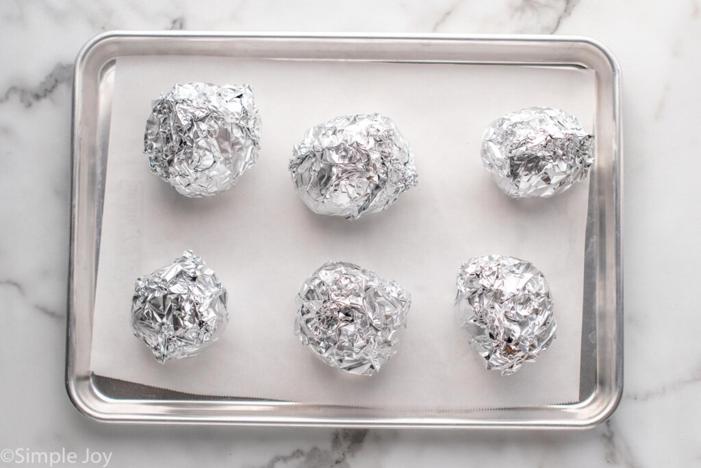 Overhead view of beets wrapped in foil on baking sheet for Beet Salad recipe.