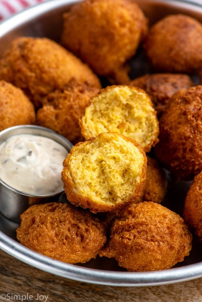 Bowl of Hush Puppies with one broken in half, bowl of dipping sauce