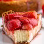 Front view of a slice of Strawberry Cheesecake with a bite taken out of it