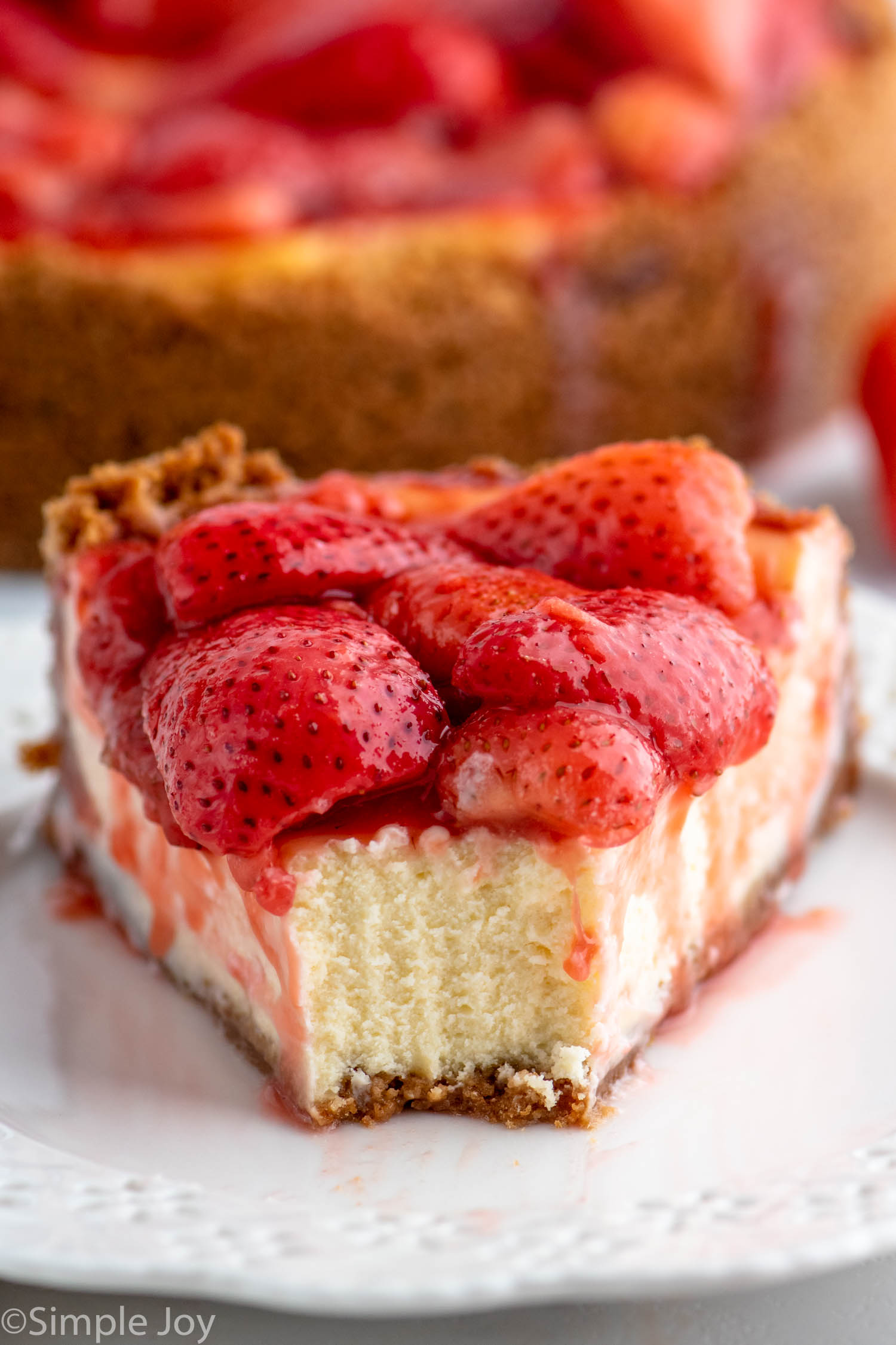 Front view of a slice of Strawberry Cheesecake with a bite taken out of it