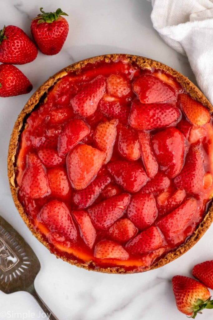 Overhead view of Strawberry Cheesecake with strawberries and serving spatula beside.