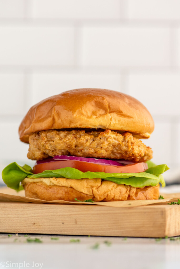 Side view of Air Fryer Turkey Burger served on a bun with lettuce, tomato, and onion.
