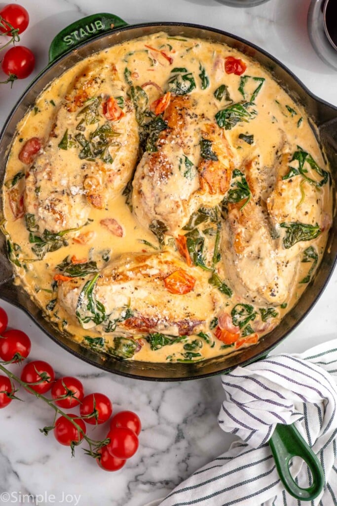 Overhead view of a skillet of Tuscan Chicken with cherry tomatoes beside.