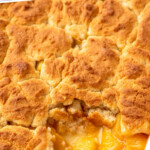 Pinterest graphic for peach cobbler recipe. Text says, "the best peach cobbler simplejoy.com." Image shows a baking dish of peach cobbler with one piece missing.
