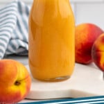 Pinterest graphic for Peach syrup recipe. Image shows side view of a jar of Peach syrup with peaches beside. Text says, "Peach syrup simplejoy.com"