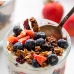 Pinterest graphic for yogurt parfait recipe. Text says, "the best yogurt parfait simplejoy.com." Image shows a yogurt parfait with a spoon, garnished with granola, blueberries, and chopped strawberries.
