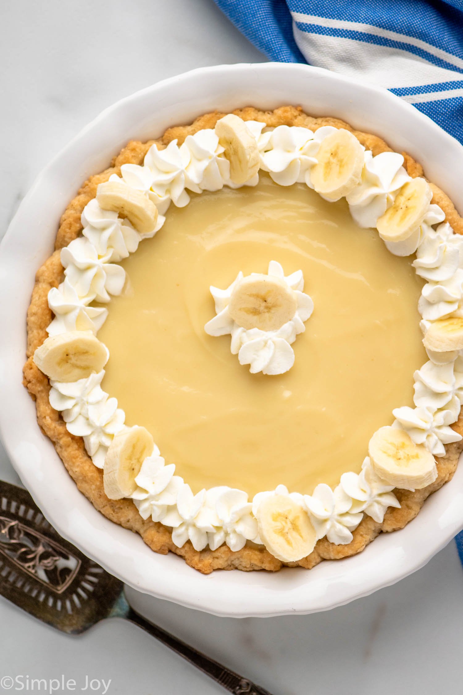 Overhead view of Banana Cream Pie garnished with whipped cream and slices of banana