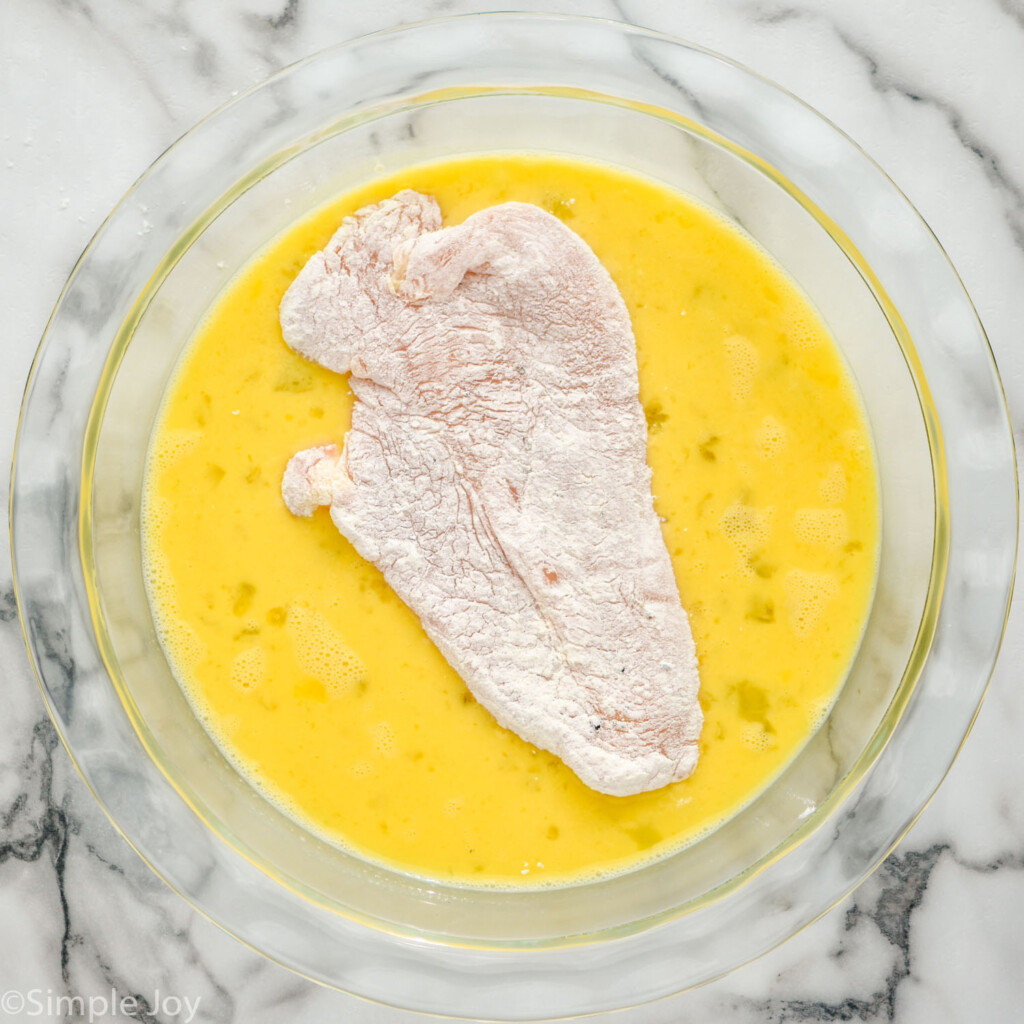 chicken breast coated in flour in a bread bath for a chicken parmesan sandwich