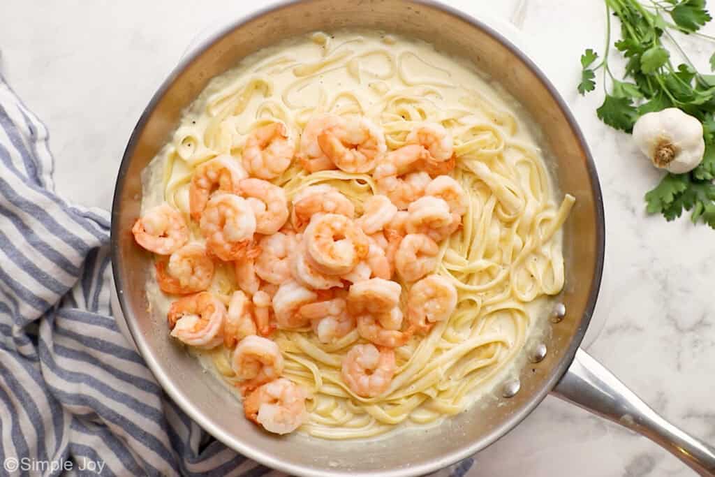 overhead of cooked shrimp in a skillet with fettuccine Alfredo