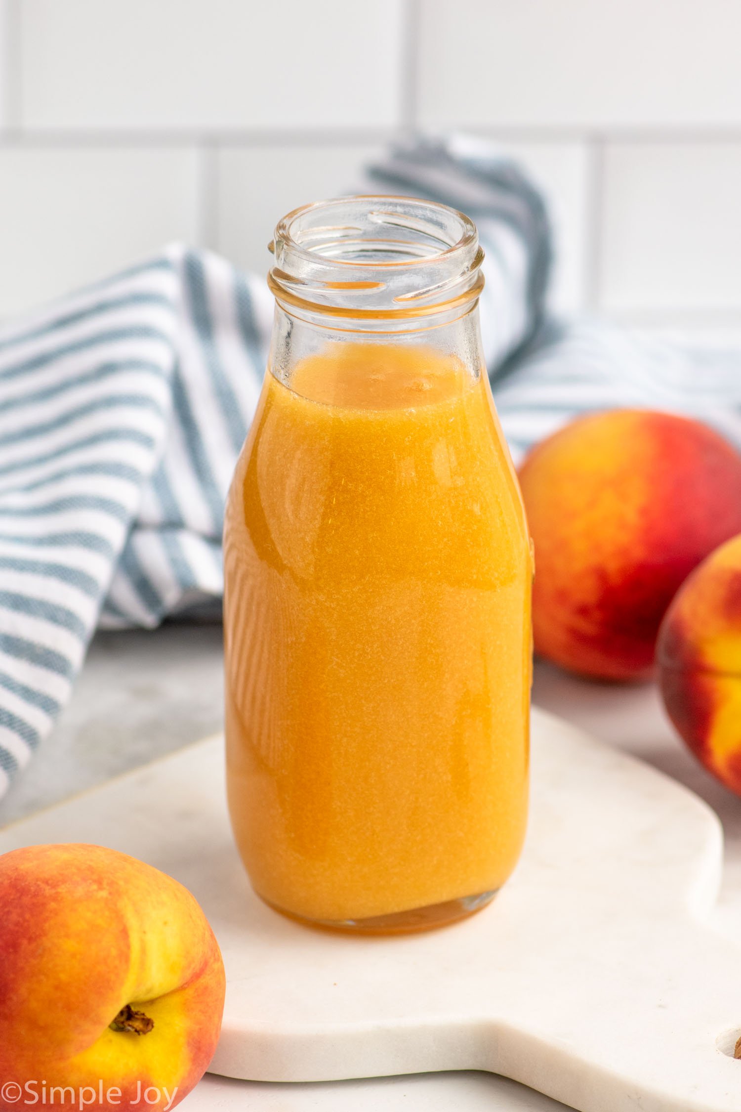 Jar of Peach syrup with peaches beside