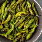 Overhead view of a skillet of shishito peppers garnished with salt