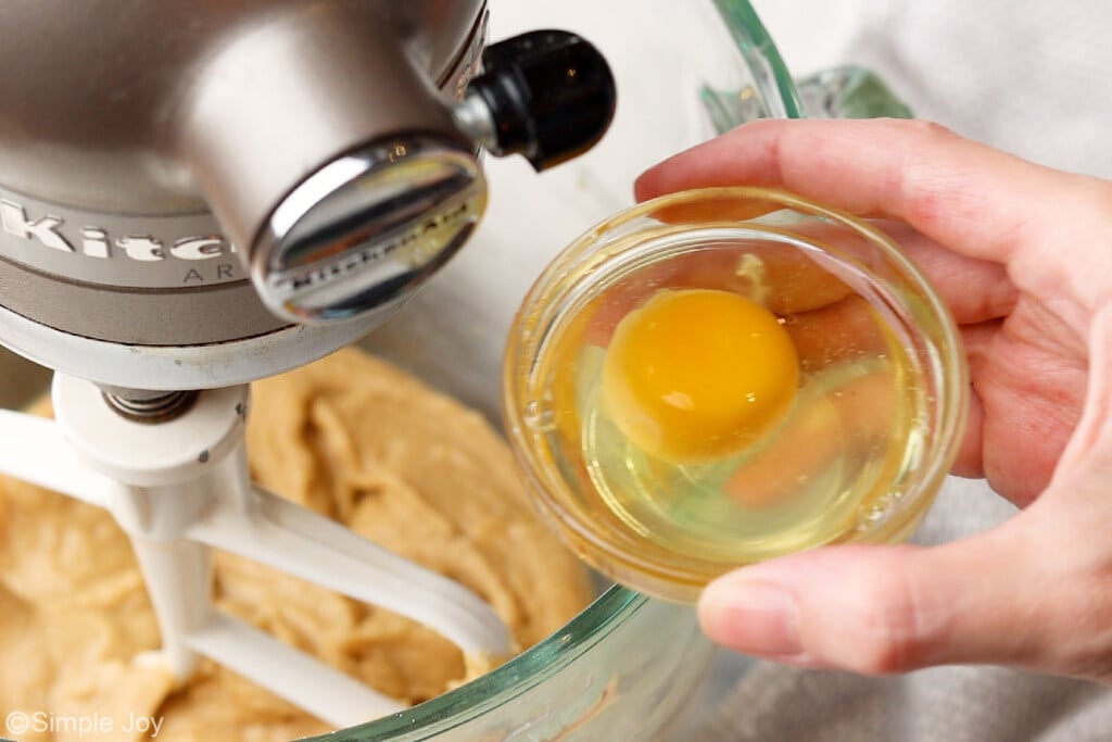 a small bowl with an egg above a stand mixer bowl