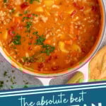 Pinterest graphic for Manhattan Clam Chowder recipe. Overhead view of a pot of Manhattan Clam Chowder with bread beside. Text says, "the absolute best Manhattan Clam Chowder simplejoy.com."