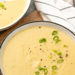 Pinterest graphic for potato leek soup recipe. Text says, "the best potato leek soup simpejoy.com." Image shows a bowl of potato leek soup garnished with chopped green onions, bread beside.