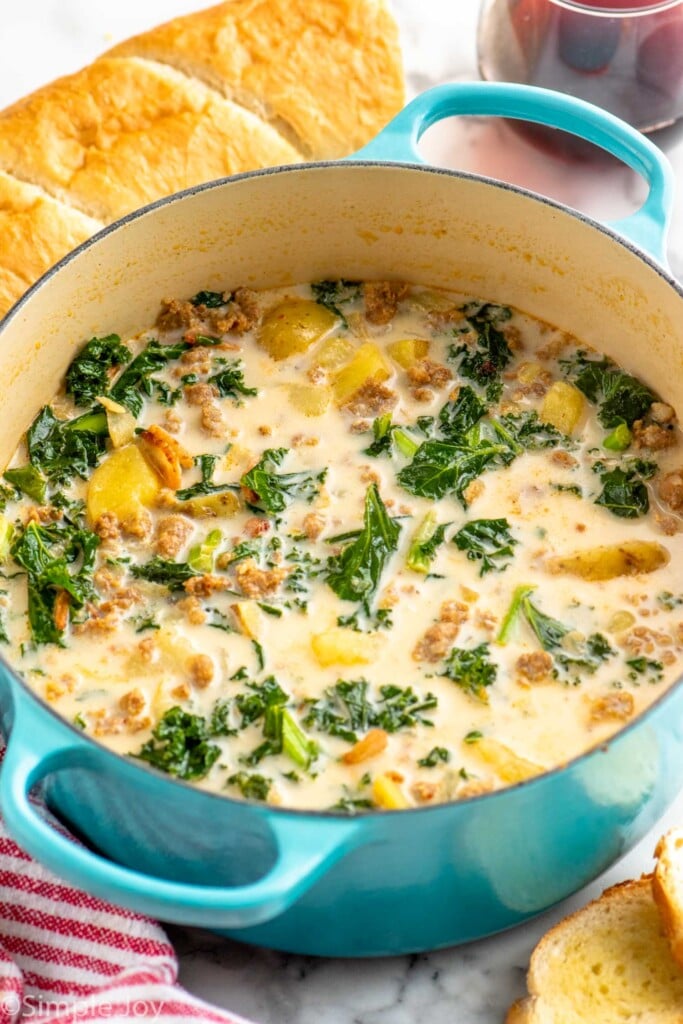 Pot of Zuppa Toscana with bread and glass of red wine beside - 4