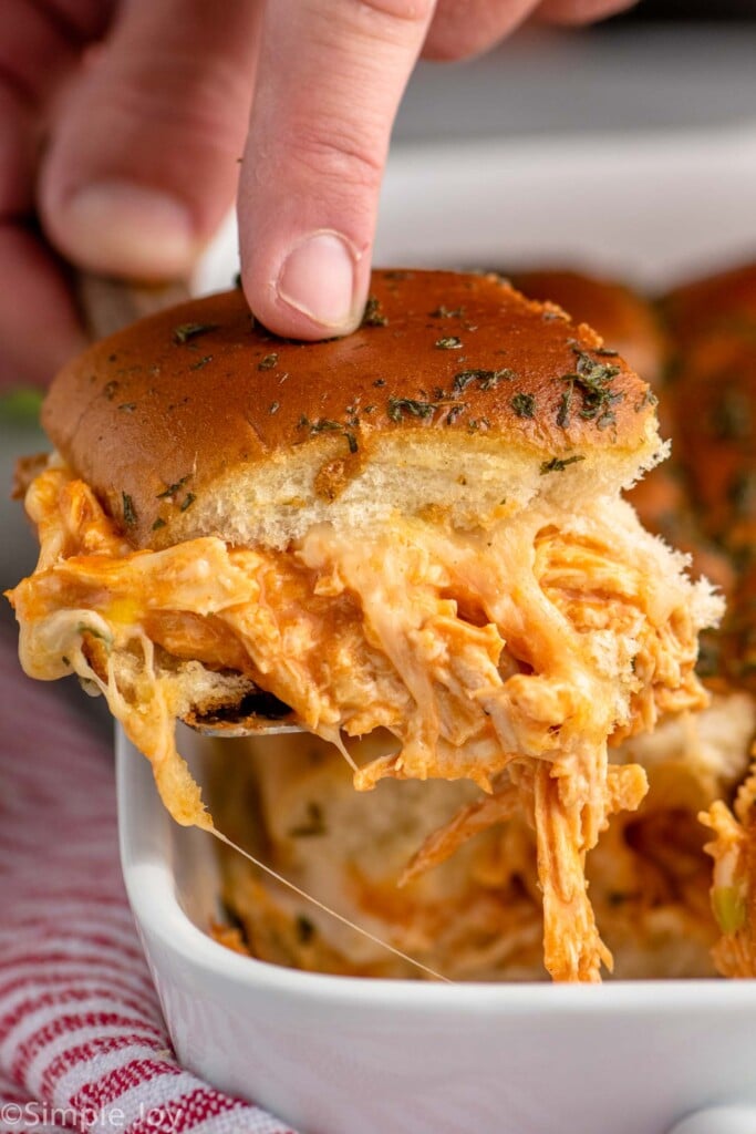 Close up photo of person's hand serving a Buffalo Chicken Slider out of baking dish - 9