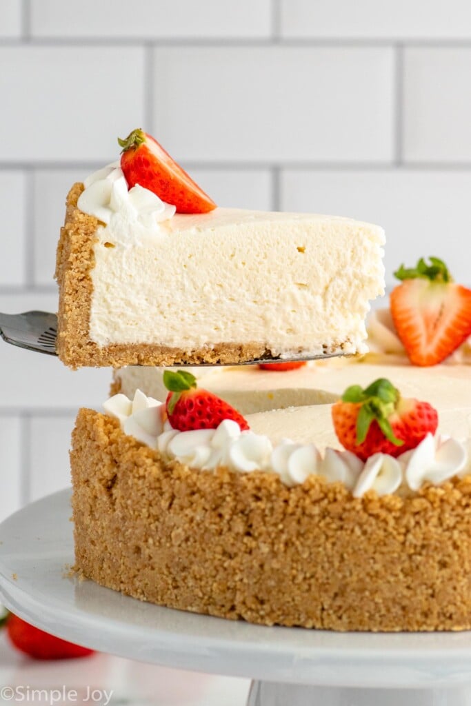 Side view of slice of No Bake Cheesecake being lifted from No Bake Cheesecake garnished with whipped cream and strawberries - 14