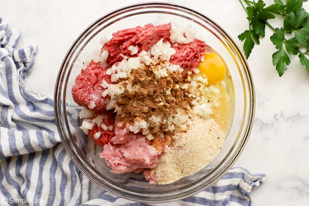 overhead of meat, onions, spices, breadcrumbs and egg in a bowl to make Swedish Meatballs